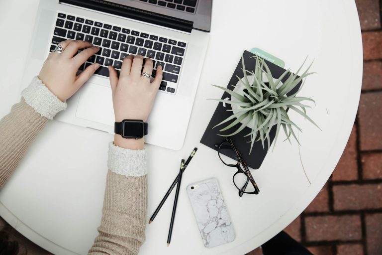 Hände an einer Laptop-Tastatur, daneben Notizbuch, Pflanze und Smartphone. Preisvergleich Internetvertrag 450€ Cashback